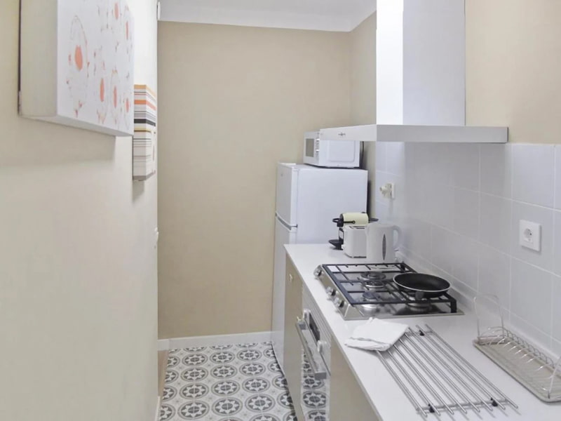 Cocina equipada con fogones, nevera y detalles minimalistas
