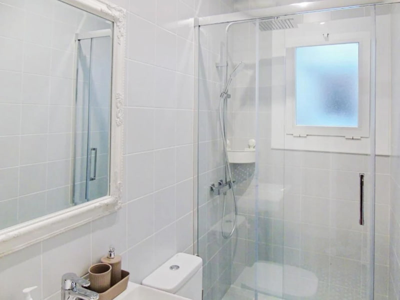 Baño moderno con ducha acristalada y acabados en tonos blancos