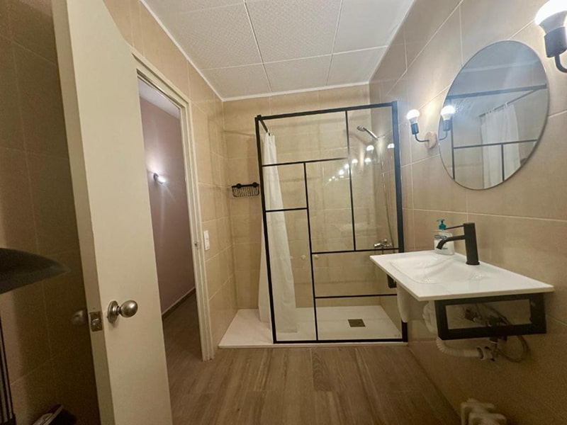 Baño moderno con ducha abierta y acabados en tonos cálidos