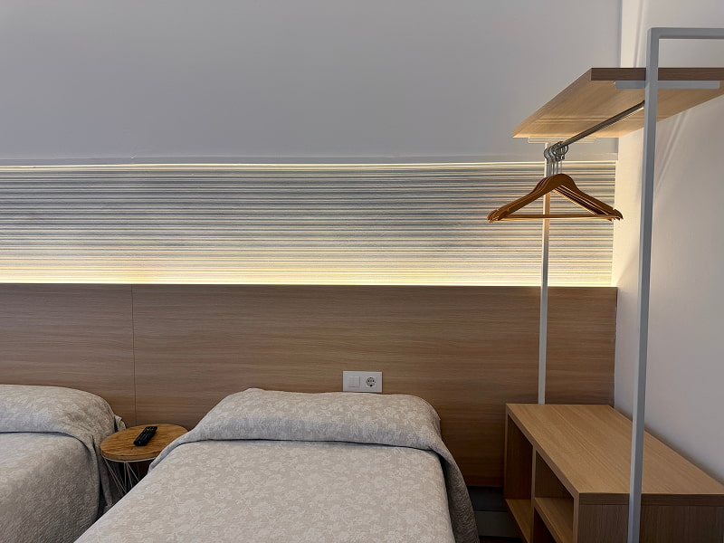 Cabecero iluminado con camas individuales y acabados en madera clara