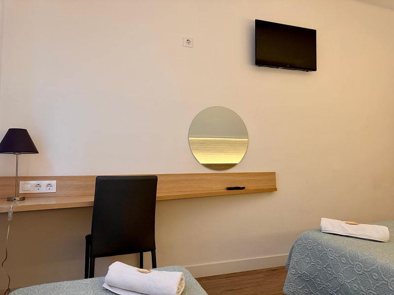 Escritorio de madera con espejo redondo y televisión en la habitación