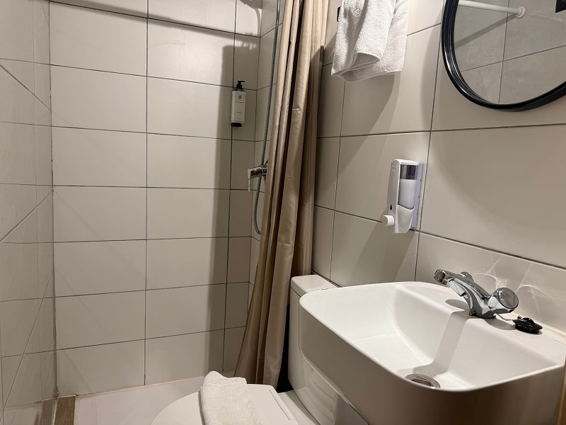 Baño moderno con ducha, lavabo y acabados en tonos claros